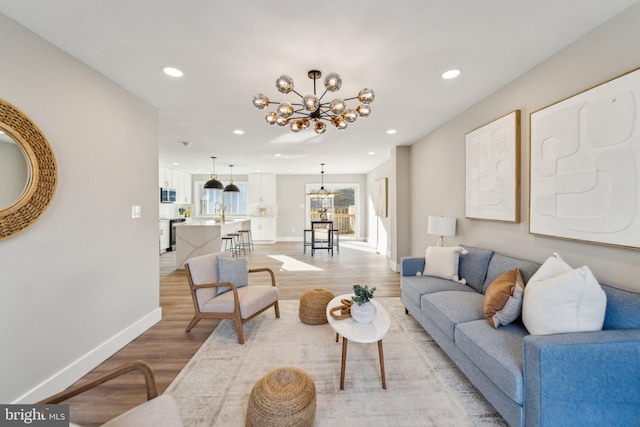 living room with recessed lighting, baseboards, light wood finished floors, and an inviting chandelier