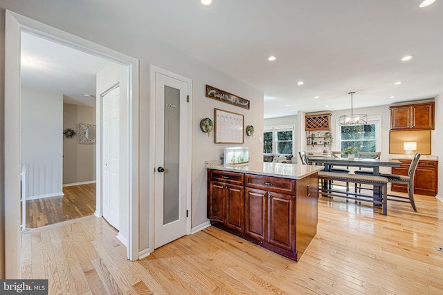 kitchen featuring pendant lighting, light wood finished floors, recessed lighting, a peninsula, and baseboards