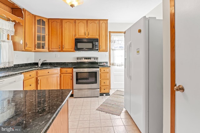 kitchen with light tile patterned floors, white appliances, a sink, brown cabinets, and glass insert cabinets