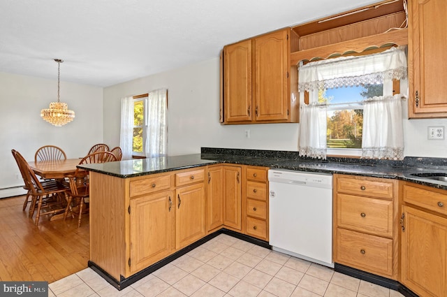 kitchen with a peninsula, dishwasher, brown cabinetry, dark stone countertops, and pendant lighting