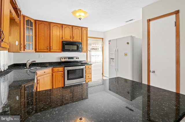 kitchen with visible vents, glass insert cabinets, stainless steel range with electric cooktop, white fridge with ice dispenser, and black microwave