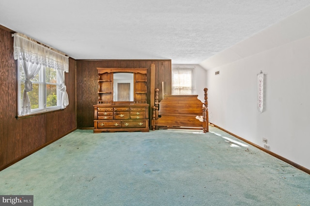 unfurnished room with wooden walls, built in features, baseboards, light colored carpet, and a textured ceiling