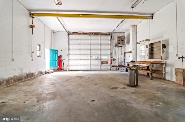 garage featuring concrete block wall, heating unit, and a workshop area