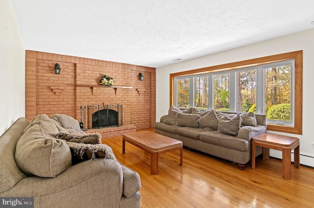 living room featuring a textured ceiling, a brick fireplace, and light wood-style flooring