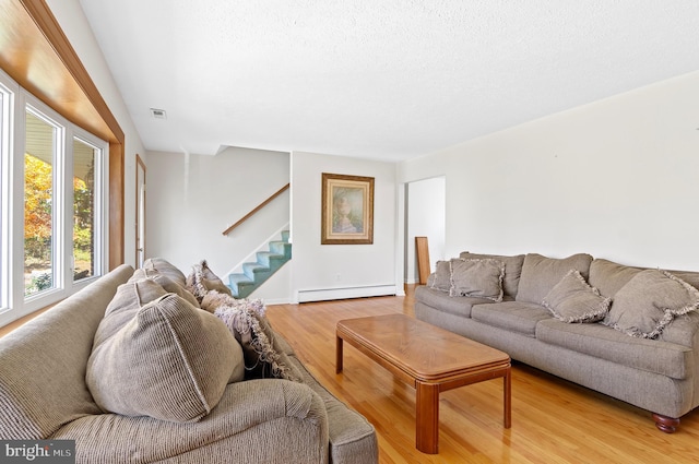 living room with visible vents, stairway, a textured ceiling, light wood-type flooring, and a baseboard heating unit