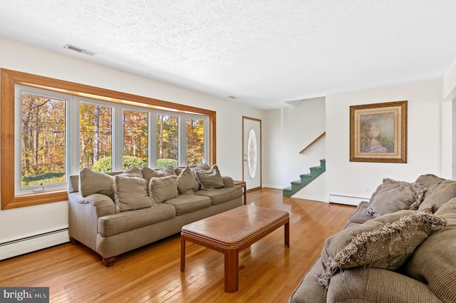 living area with stairs, light wood finished floors, a baseboard radiator, and visible vents