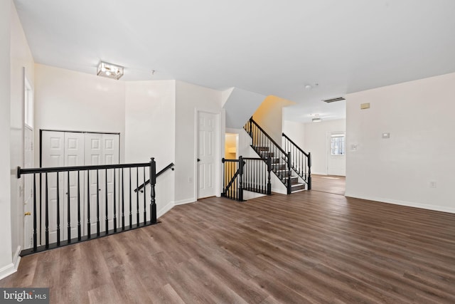 empty room featuring stairs, wood finished floors, visible vents, and baseboards