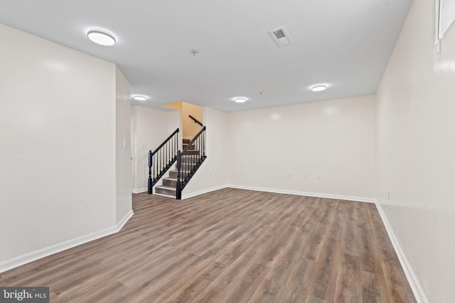 finished basement featuring stairs, visible vents, baseboards, and wood finished floors