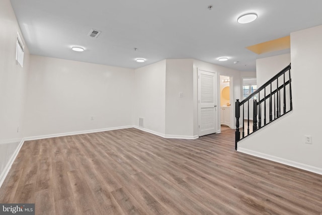 basement featuring wood finished floors, visible vents, baseboards, and stairs