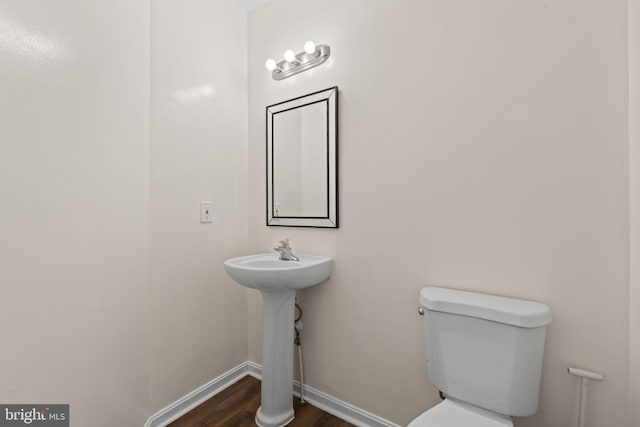 bathroom with toilet, a sink, baseboards, and wood finished floors