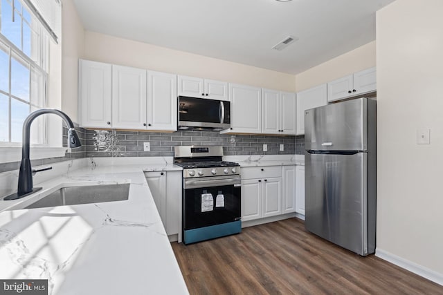 kitchen featuring stainless steel appliances, visible vents, a sink, and decorative backsplash