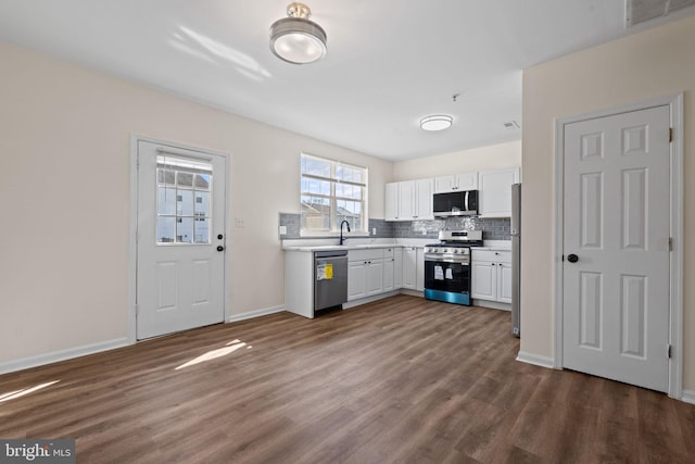 kitchen featuring stainless steel appliances, dark wood-style flooring, visible vents, white cabinets, and decorative backsplash