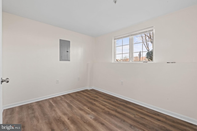 unfurnished room featuring electric panel, baseboards, and wood finished floors