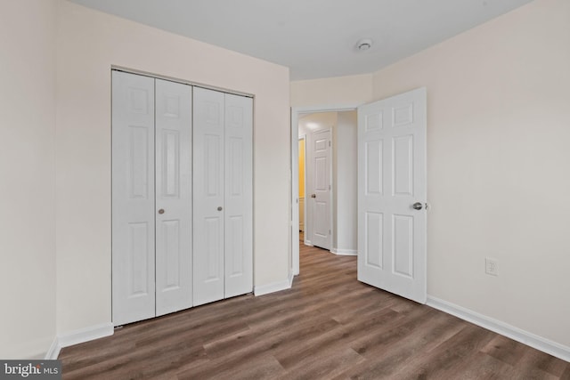 unfurnished bedroom with a closet, baseboards, and wood finished floors