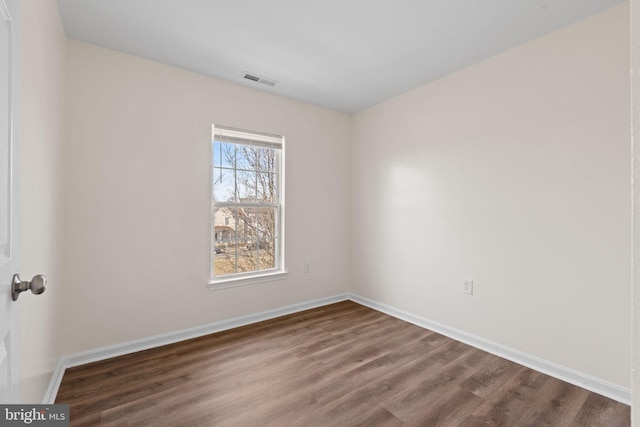 spare room featuring visible vents, dark wood finished floors, and baseboards