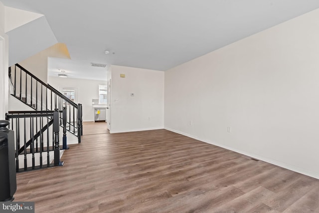 unfurnished living room with baseboards, visible vents, stairway, and wood finished floors