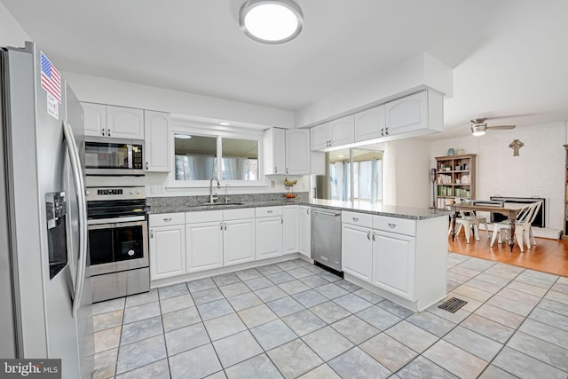 kitchen with visible vents, a sink, white cabinetry, stainless steel appliances, and a peninsula