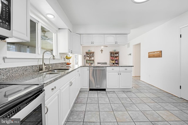 kitchen with light stone counters, white cabinets, stainless steel appliances, and a sink