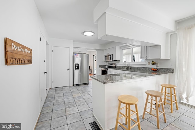 kitchen with visible vents, a breakfast bar area, appliances with stainless steel finishes, a peninsula, and white cabinets