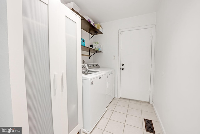 clothes washing area featuring light tile patterned floors, visible vents, baseboards, laundry area, and separate washer and dryer