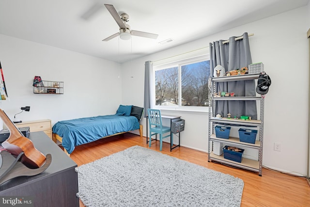 bedroom with a ceiling fan, wood finished floors, and visible vents