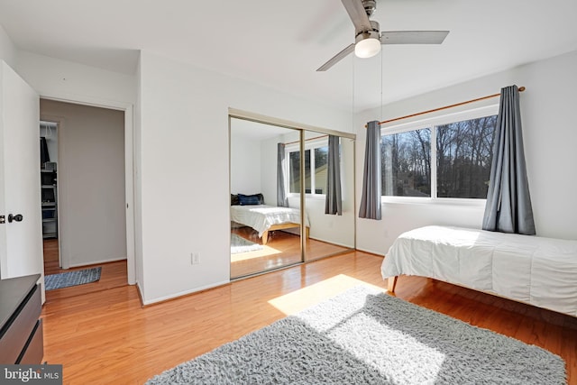 bedroom with a closet, baseboards, light wood-type flooring, and ceiling fan