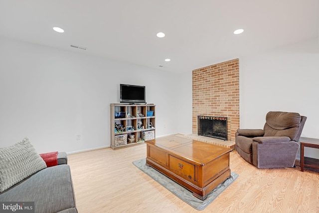 living room with recessed lighting, a fireplace, visible vents, and light wood-type flooring