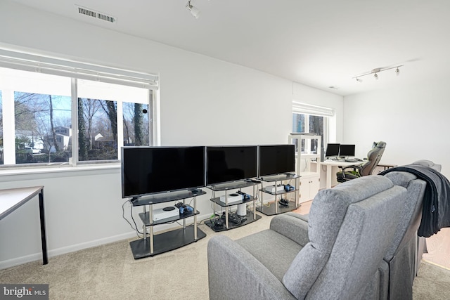 carpeted living area with rail lighting, baseboards, and visible vents