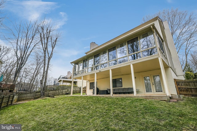 back of house featuring a yard, a fenced backyard, a chimney, and french doors