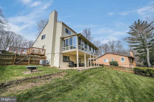 back of property with a patio area, a lawn, a fenced backyard, and a chimney