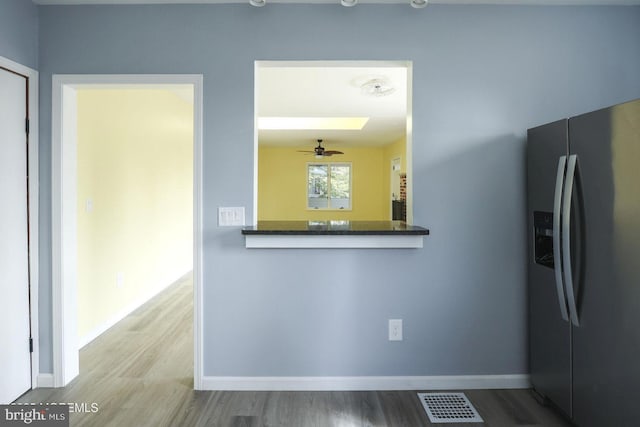 kitchen with stainless steel fridge, visible vents, baseboards, and wood finished floors