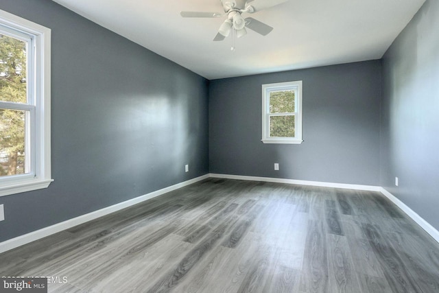 empty room featuring dark wood-type flooring, a ceiling fan, and baseboards