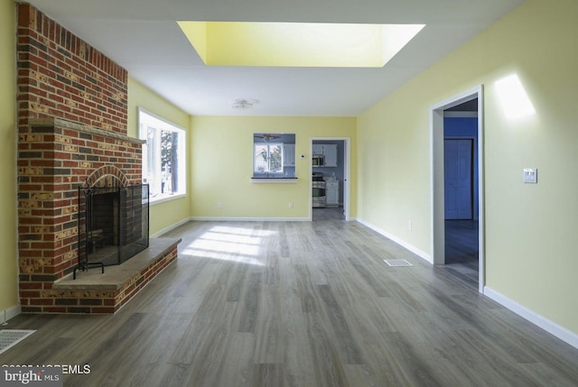 unfurnished living room featuring a brick fireplace, baseboards, and dark wood-style floors