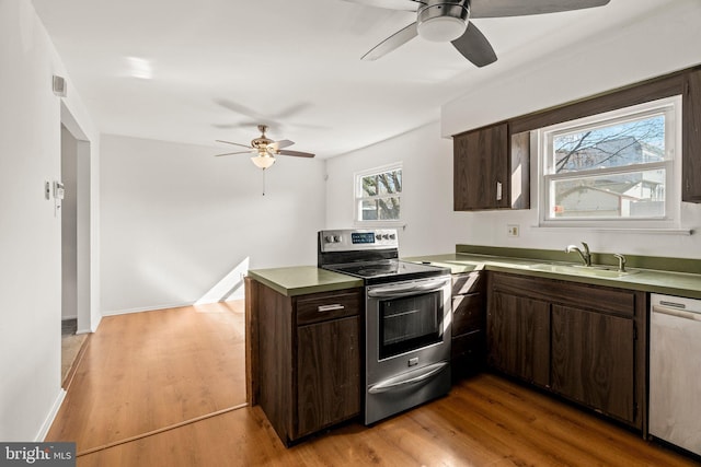 kitchen featuring a peninsula, appliances with stainless steel finishes, a sink, and dark brown cabinetry