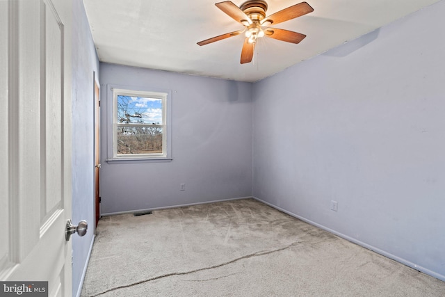 empty room with carpet, visible vents, and ceiling fan