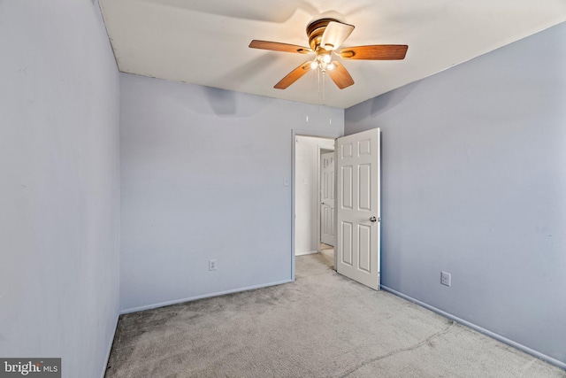 carpeted spare room featuring a ceiling fan and baseboards