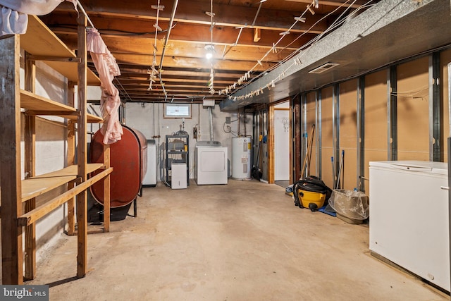 basement with visible vents, electric water heater, washing machine and clothes dryer, heating fuel, and refrigerator