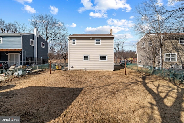 back of property featuring a fenced backyard, a yard, and a chimney