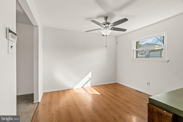 unfurnished room featuring baseboards, visible vents, ceiling fan, and wood finished floors