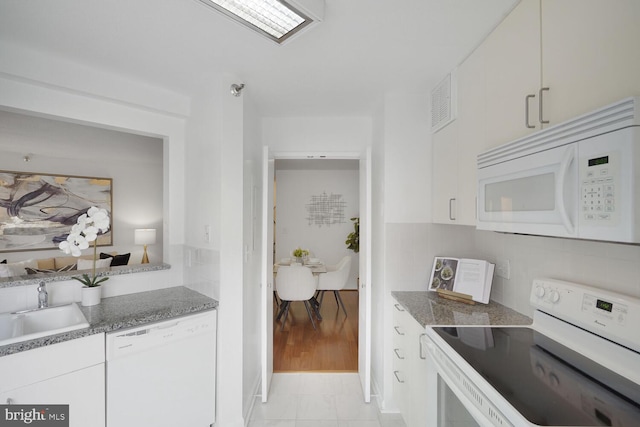 kitchen with white appliances, white cabinetry, backsplash, and a sink