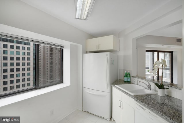 kitchen featuring white appliances, visible vents, stone counters, white cabinetry, and a sink