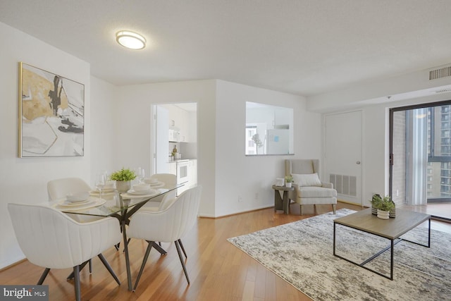 dining room featuring visible vents, a textured ceiling, and light wood finished floors