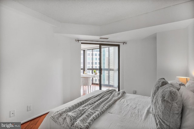 bedroom featuring a textured ceiling, wood finished floors, visible vents, and baseboards