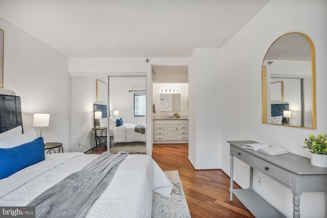 bedroom featuring ensuite bath, a closet, wood finished floors, and baseboards