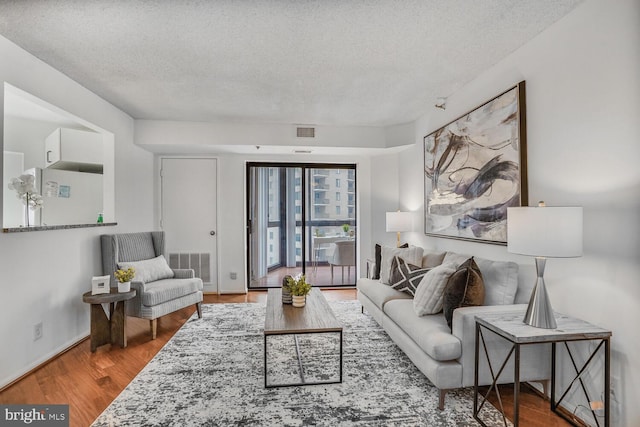 living room featuring a textured ceiling, wood finished floors, and visible vents