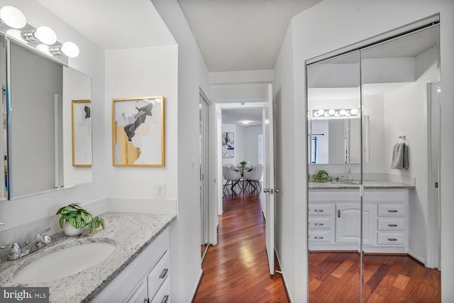 bathroom featuring two vanities, a sink, and wood finished floors