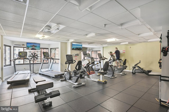 workout area with a paneled ceiling, a healthy amount of sunlight, and baseboards