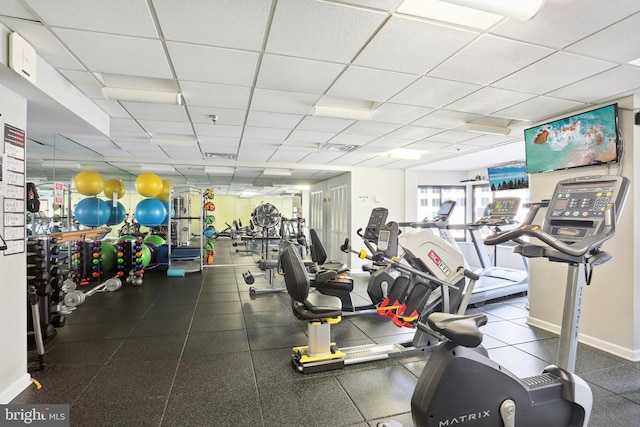 gym with a drop ceiling and baseboards