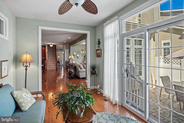 interior space with ceiling fan, wood finished floors, visible vents, baseboards, and stairs