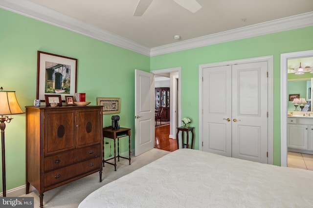 bedroom with light colored carpet, a ceiling fan, a closet, ensuite bath, and crown molding